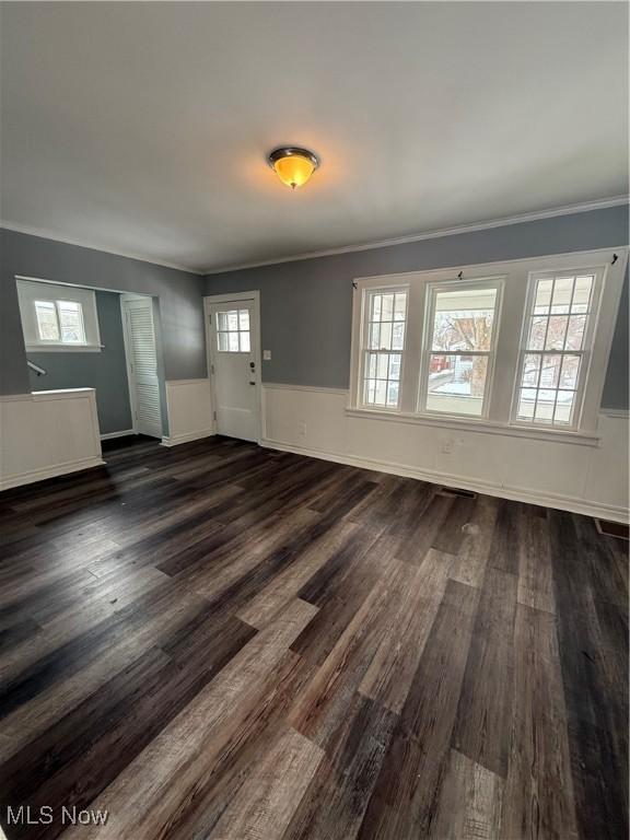 entrance foyer with dark wood-style floors, ornamental molding, and wainscoting