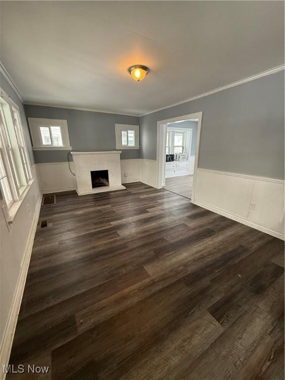 unfurnished living room with a healthy amount of sunlight, a wainscoted wall, and a fireplace