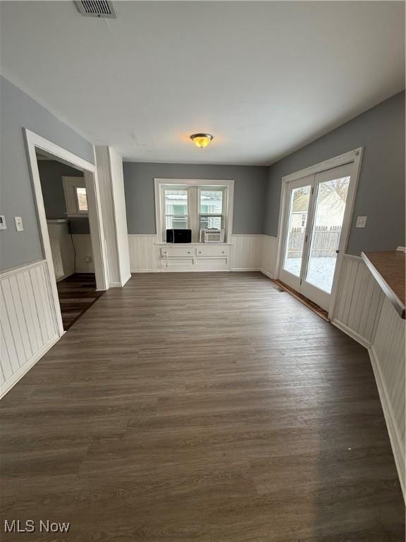 interior space with a wainscoted wall, visible vents, and dark wood-style flooring