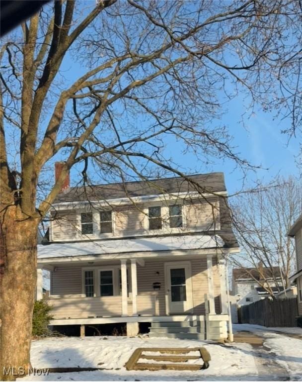 view of front of house featuring covered porch, a chimney, and fence