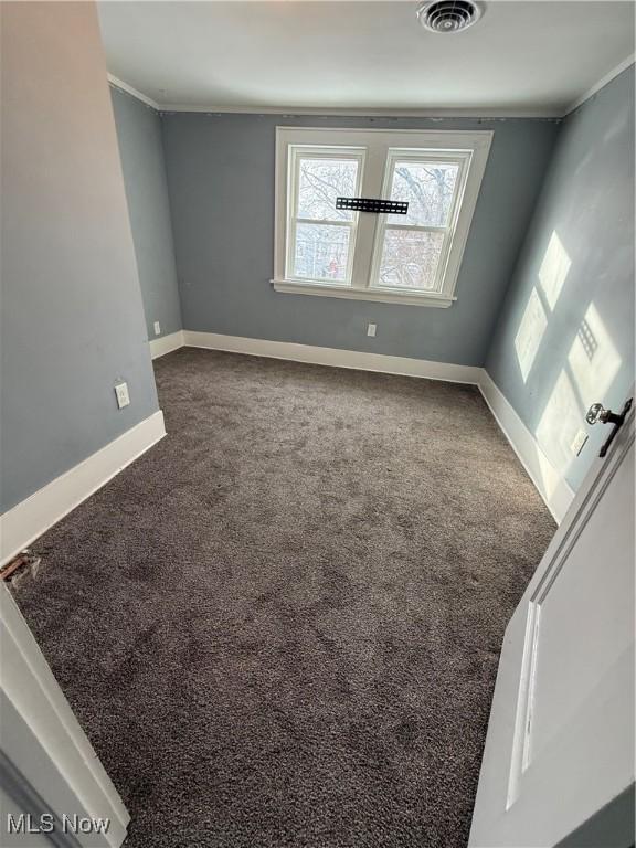 spare room featuring baseboards, carpet flooring, visible vents, and crown molding