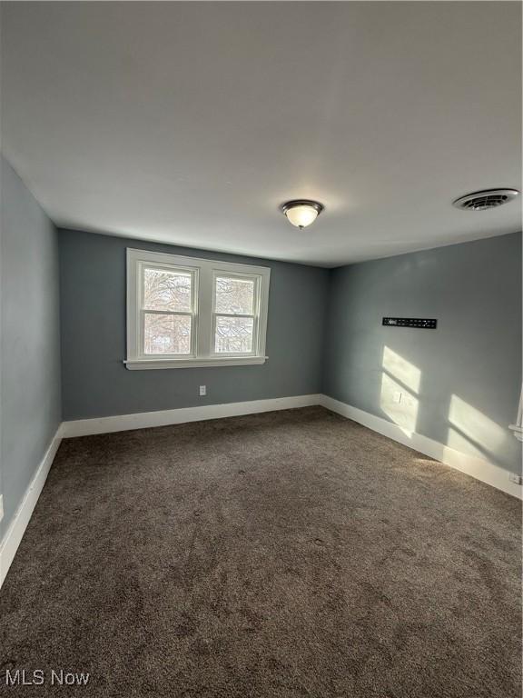 spare room with carpet floors, baseboards, and visible vents