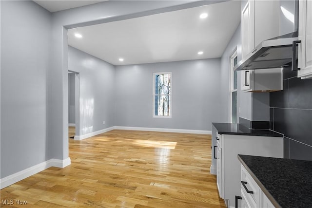 kitchen with wall chimney exhaust hood, light hardwood / wood-style flooring, and white cabinets