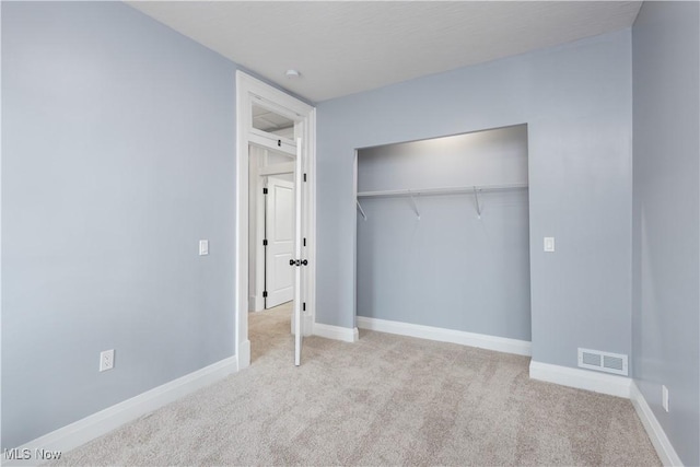 unfurnished bedroom featuring a closet and light carpet