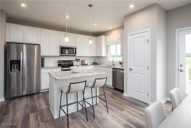 kitchen with sink, white cabinetry, decorative light fixtures, a kitchen island, and stainless steel appliances