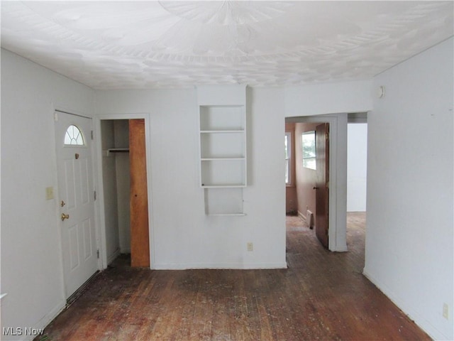 interior space featuring dark wood-style floors, plenty of natural light, and baseboards