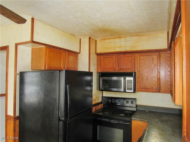 kitchen featuring a textured ceiling, black appliances, brown cabinetry, and dark countertops