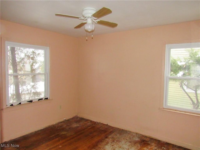 empty room with dark wood finished floors, a ceiling fan, and a healthy amount of sunlight