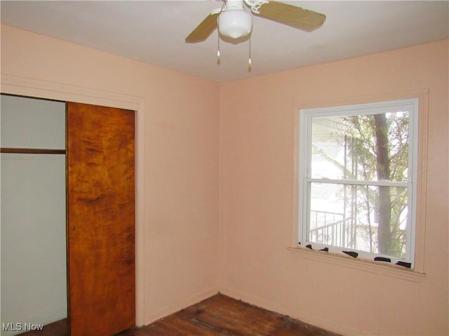 unfurnished bedroom with a ceiling fan, a closet, multiple windows, and baseboards