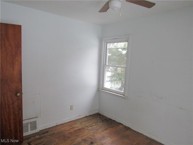 empty room featuring ceiling fan, visible vents, and dark wood finished floors