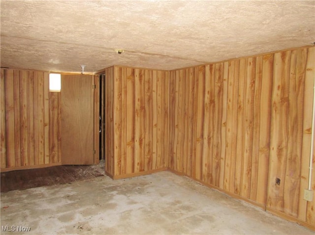 below grade area with wooden walls and a textured ceiling