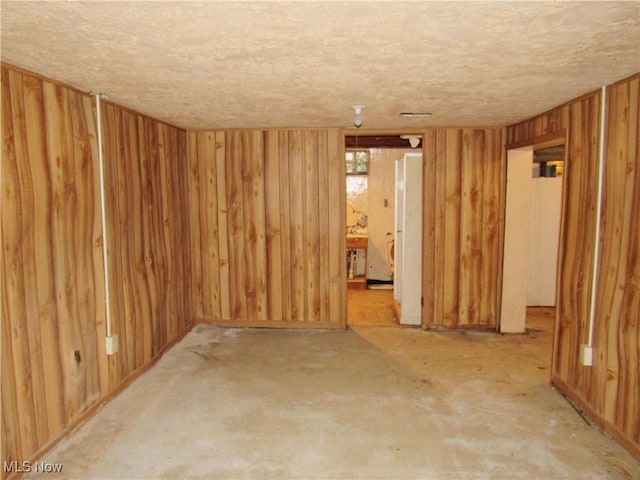 empty room featuring wood walls and a textured ceiling