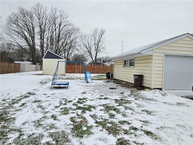 snowy yard featuring a storage shed and a garage