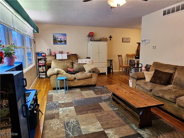 living room with hardwood / wood-style floors, a textured ceiling, and ceiling fan