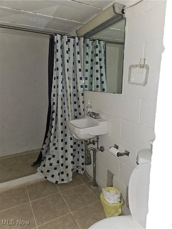 bathroom with a shower with curtain, toilet, tile patterned flooring, and sink