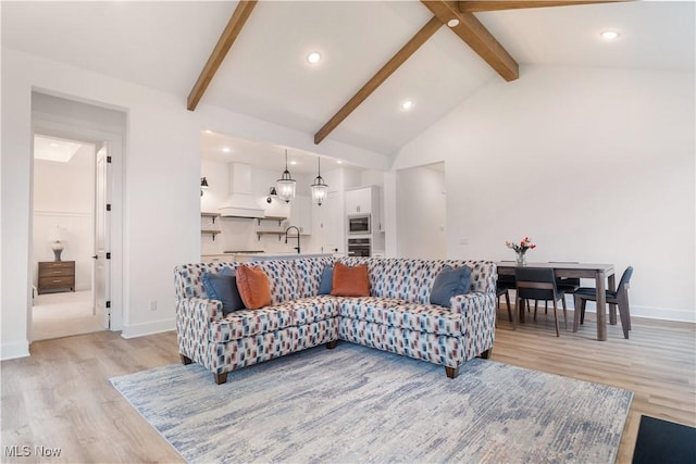 living room with high vaulted ceiling, light wood-type flooring, sink, and beam ceiling