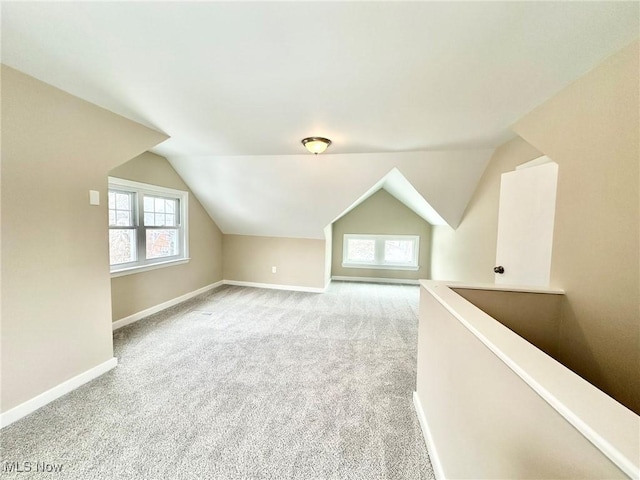 additional living space featuring vaulted ceiling, a healthy amount of sunlight, and light carpet