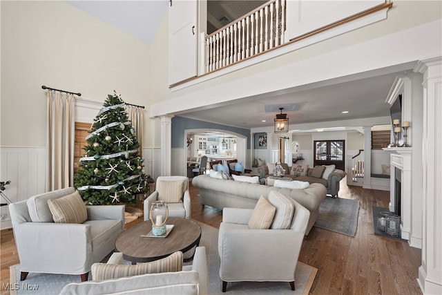 living room with hardwood / wood-style floors, a high ceiling, and ornate columns