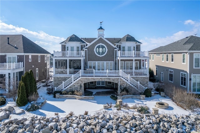 snow covered back of property with a balcony and a fire pit