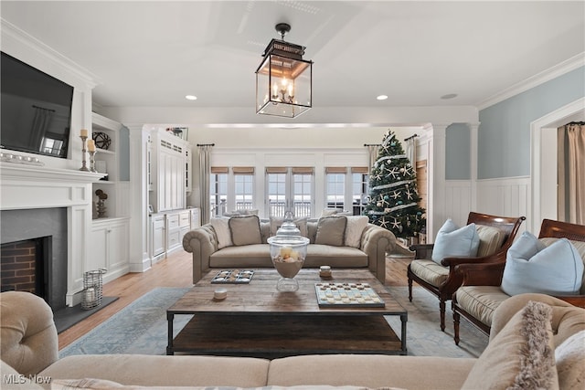 living room featuring light hardwood / wood-style floors, ornamental molding, and decorative columns