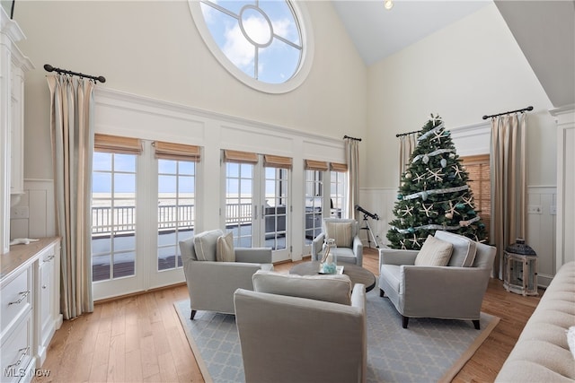 living room with light hardwood / wood-style flooring, high vaulted ceiling, and french doors