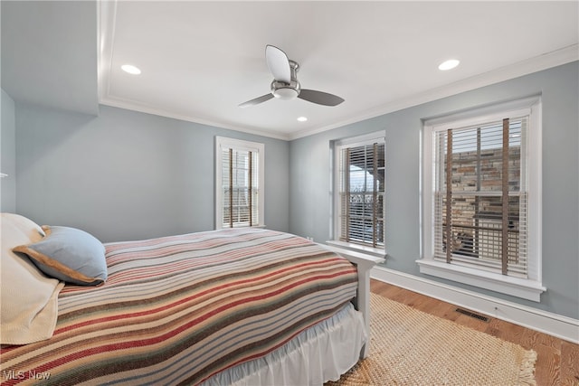 bedroom with hardwood / wood-style flooring, crown molding, and ceiling fan