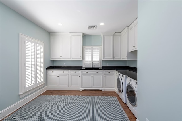 washroom with cabinets, independent washer and dryer, sink, and hardwood / wood-style flooring