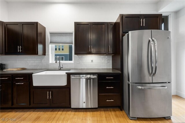 2280 City View Dr, Cleveland, OH 44113 - kitchen with sink, appliances with stainless steel finishes, backsplash, dark brown cabinetry, and light wood-type flooring