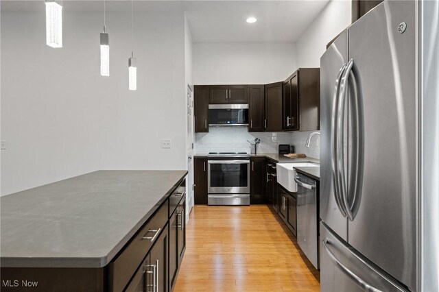 2280 City View Dr, Cleveland, OH 44113 - kitchen with sink, hanging light fixtures, stainless steel appliances, light hardwood / wood-style floors, and decorative backsplash