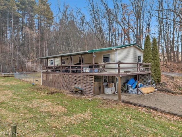 rear view of house featuring a wooden deck and a yard