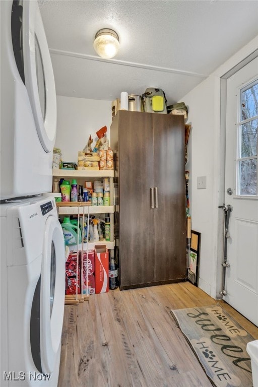 laundry area with stacked washer / dryer and hardwood / wood-style floors