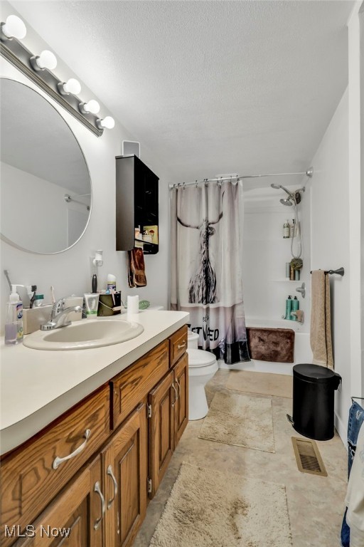 full bathroom featuring shower / bath combo, vanity, a textured ceiling, and toilet