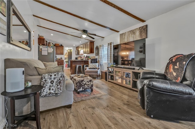 living room featuring ceiling fan, light wood-type flooring, and beam ceiling