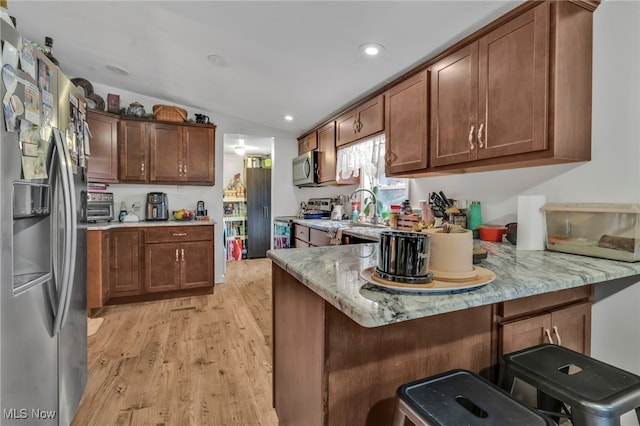 kitchen featuring a kitchen bar, kitchen peninsula, and appliances with stainless steel finishes