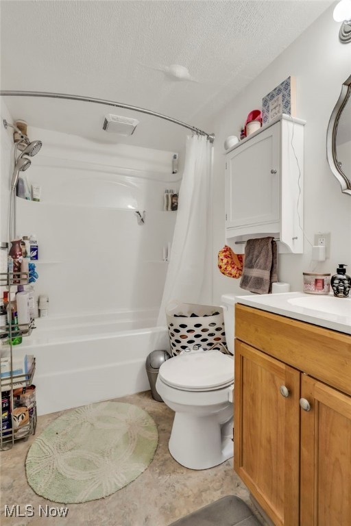 full bathroom with shower / tub combo with curtain, vanity, toilet, and a textured ceiling