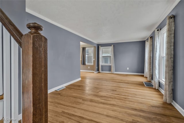 unfurnished living room featuring ornamental molding, a wealth of natural light, and light hardwood / wood-style floors