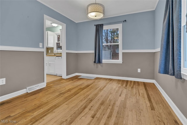 empty room featuring ornamental molding and light wood-type flooring