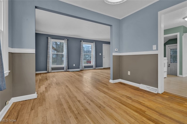 unfurnished living room featuring ornamental molding and light wood-type flooring