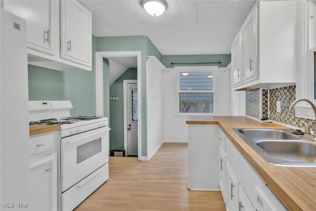 kitchen featuring tasteful backsplash, white cabinetry, sink, light wood-type flooring, and white appliances