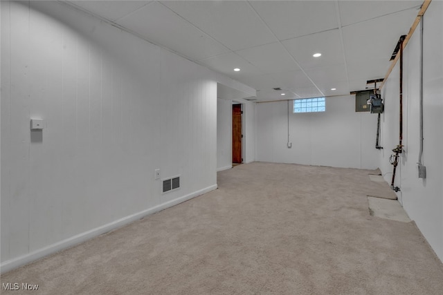 basement featuring a paneled ceiling and light colored carpet