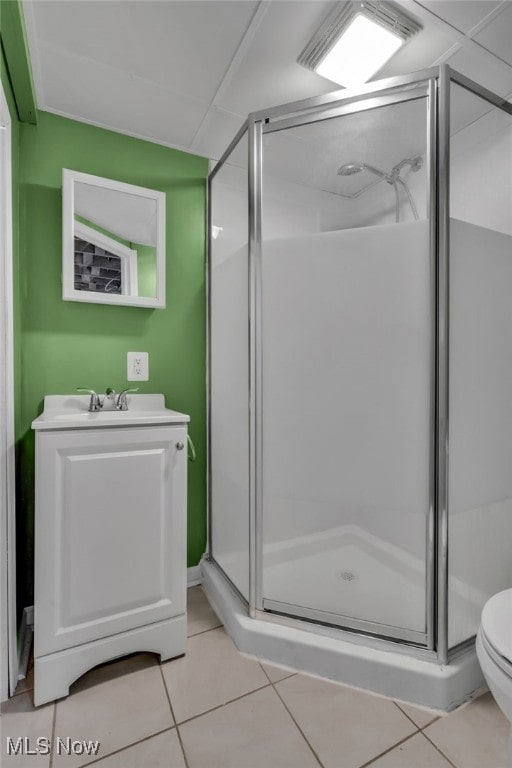 bathroom featuring tile patterned flooring, toilet, vanity, and walk in shower