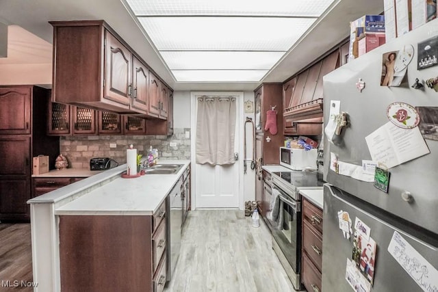 kitchen with stainless steel appliances, sink, light hardwood / wood-style flooring, and backsplash