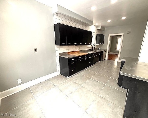 kitchen featuring tasteful backsplash, sink, light tile patterned floors, and stainless steel counters