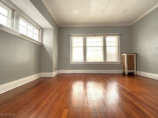 spare room with crown molding, a healthy amount of sunlight, and wood-type flooring