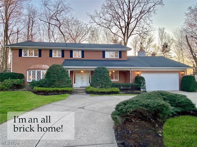 view of front of property featuring brick siding, concrete driveway, a front yard, a chimney, and an attached garage