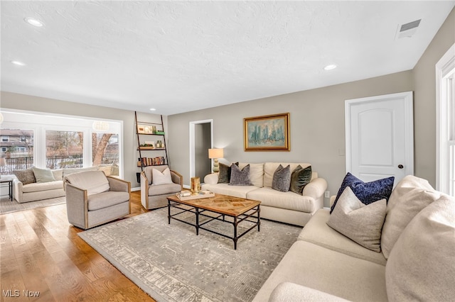 living room with a textured ceiling and light hardwood / wood-style flooring