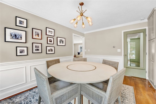 dining area with ornamental molding, a chandelier, and light hardwood / wood-style floors