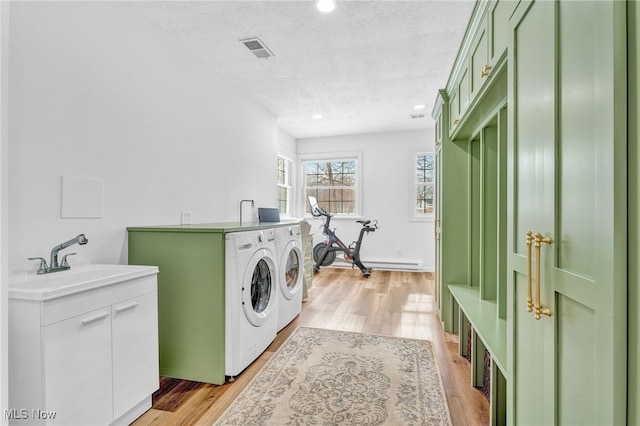 laundry area with sink, independent washer and dryer, a textured ceiling, and light wood-type flooring