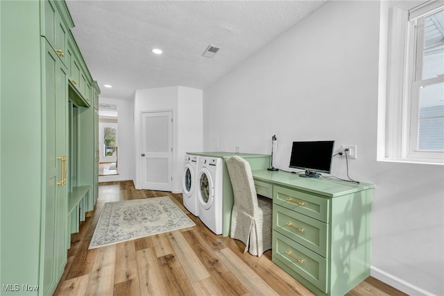 clothes washing area featuring washer and dryer, light hardwood / wood-style floors, and a textured ceiling