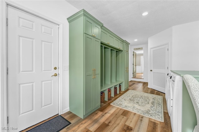 interior space featuring washing machine and dryer, wood-type flooring, and a textured ceiling